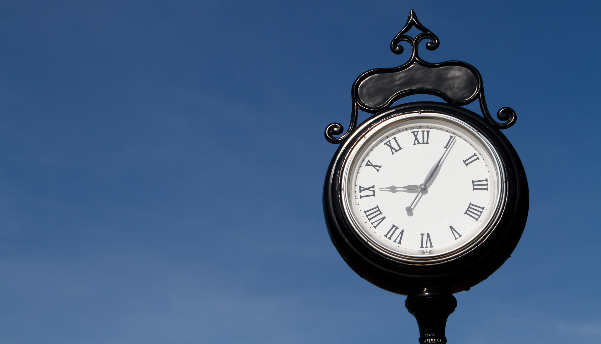 Old Black and White Street Clock with Roman Numerals Outdoors