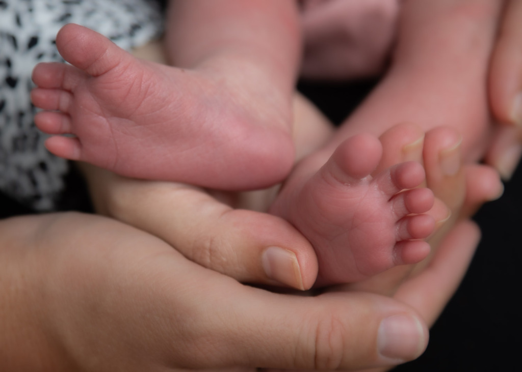 parents holding a newborn's feet