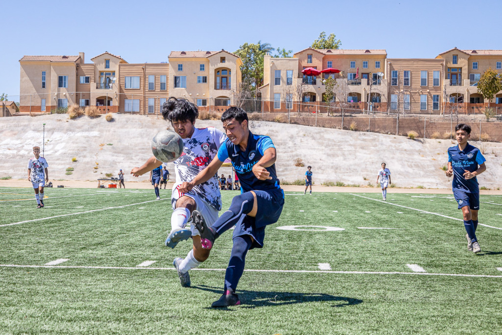 Teenaged soccer players kicking the ball with a bright hillside behind which is why I use manual mode.