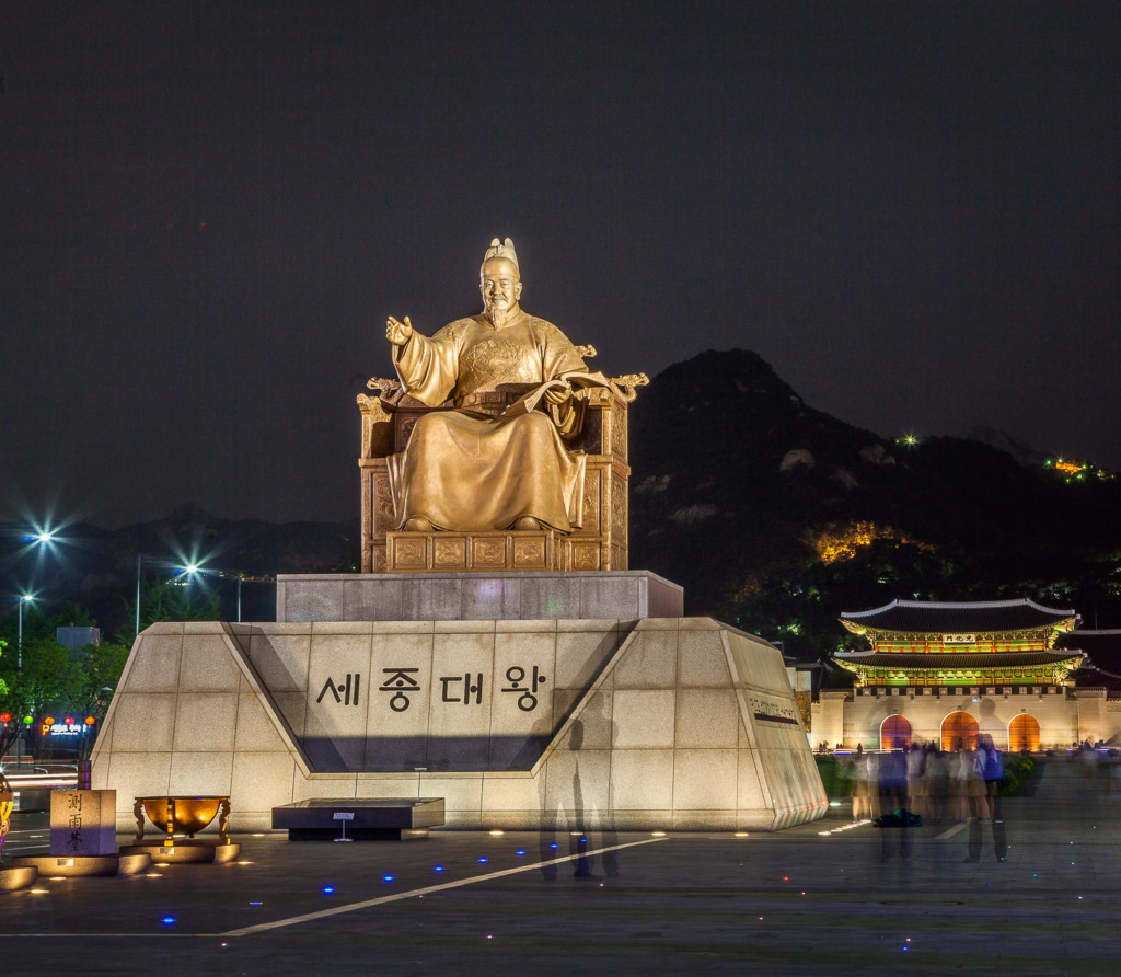 a night time image of the statue of King Sejong in Seoul, South Korea.Teh Gwanghwamun Gate can be seen behind.