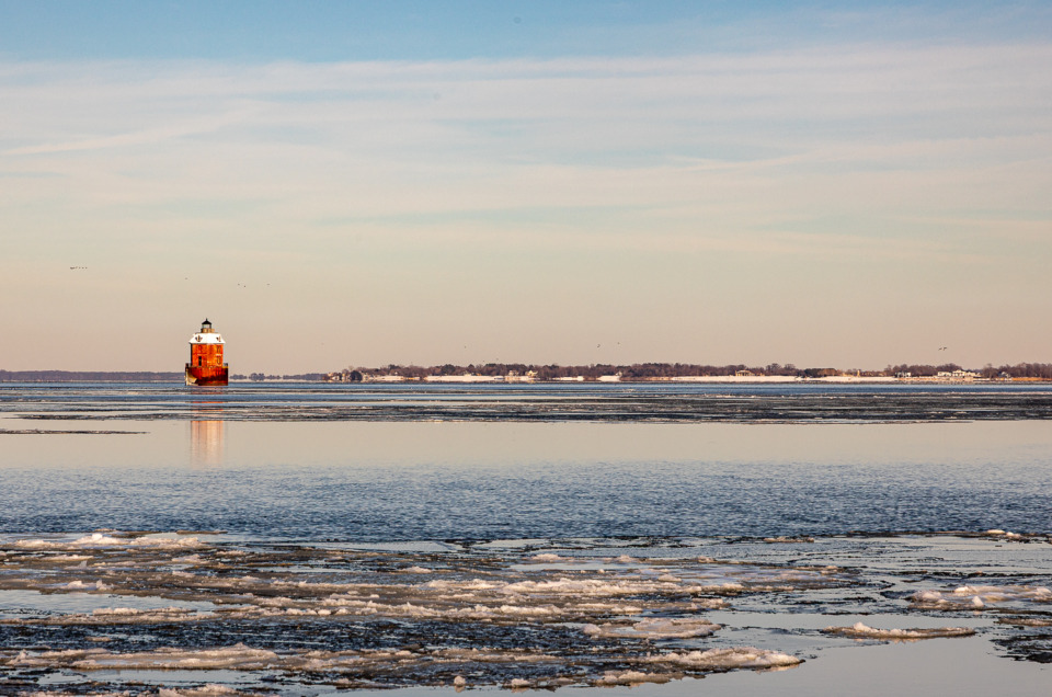 Sandy Point Shoal Lighthouse in winter, with ice floating on the water.