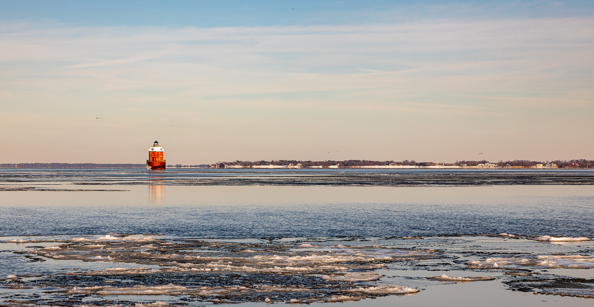 Sandy Point Shoal Lighthouse in winter, with ice floating on the water.