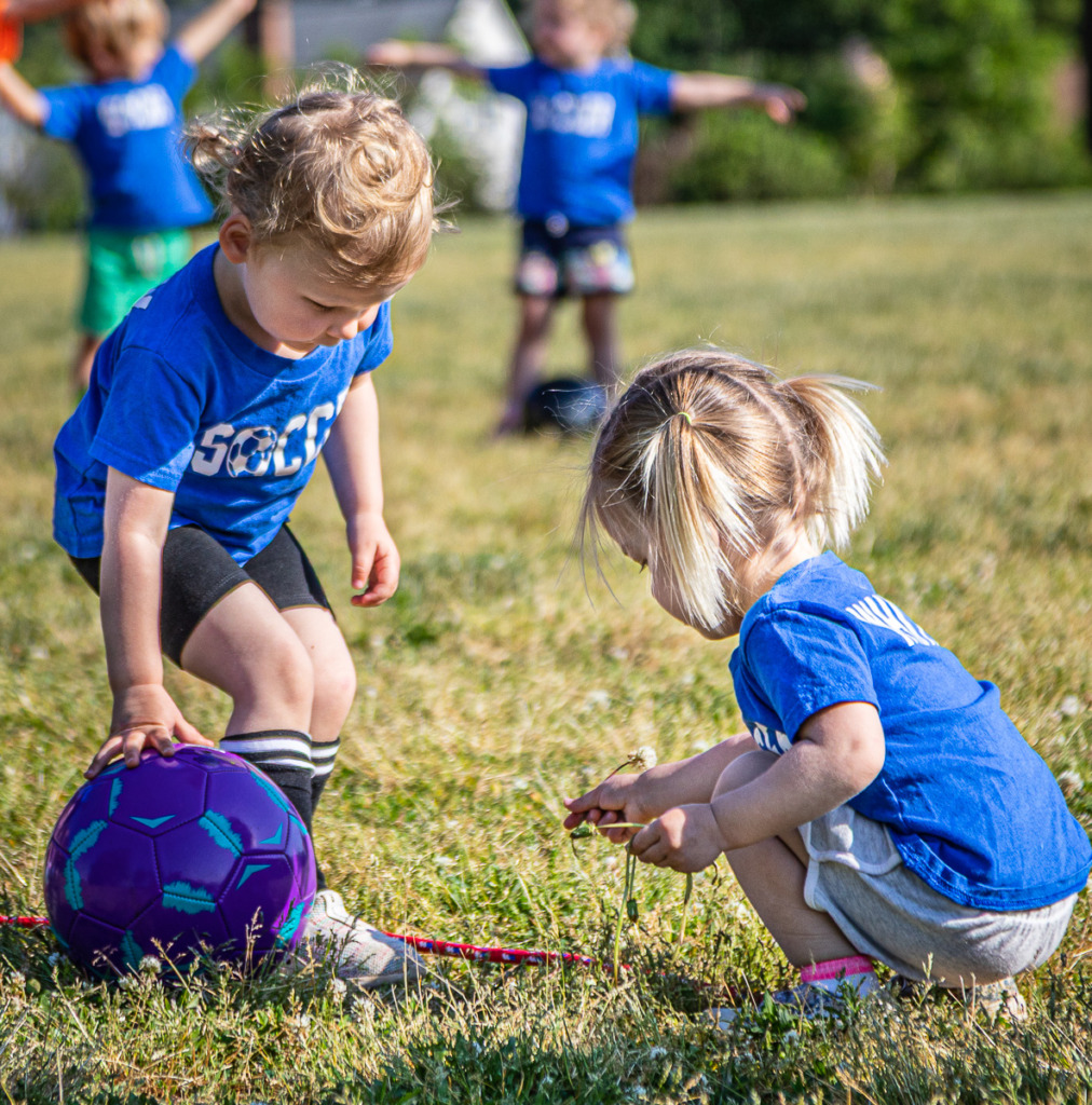 everyday photography of young childrean picking dandelions at soccer practice