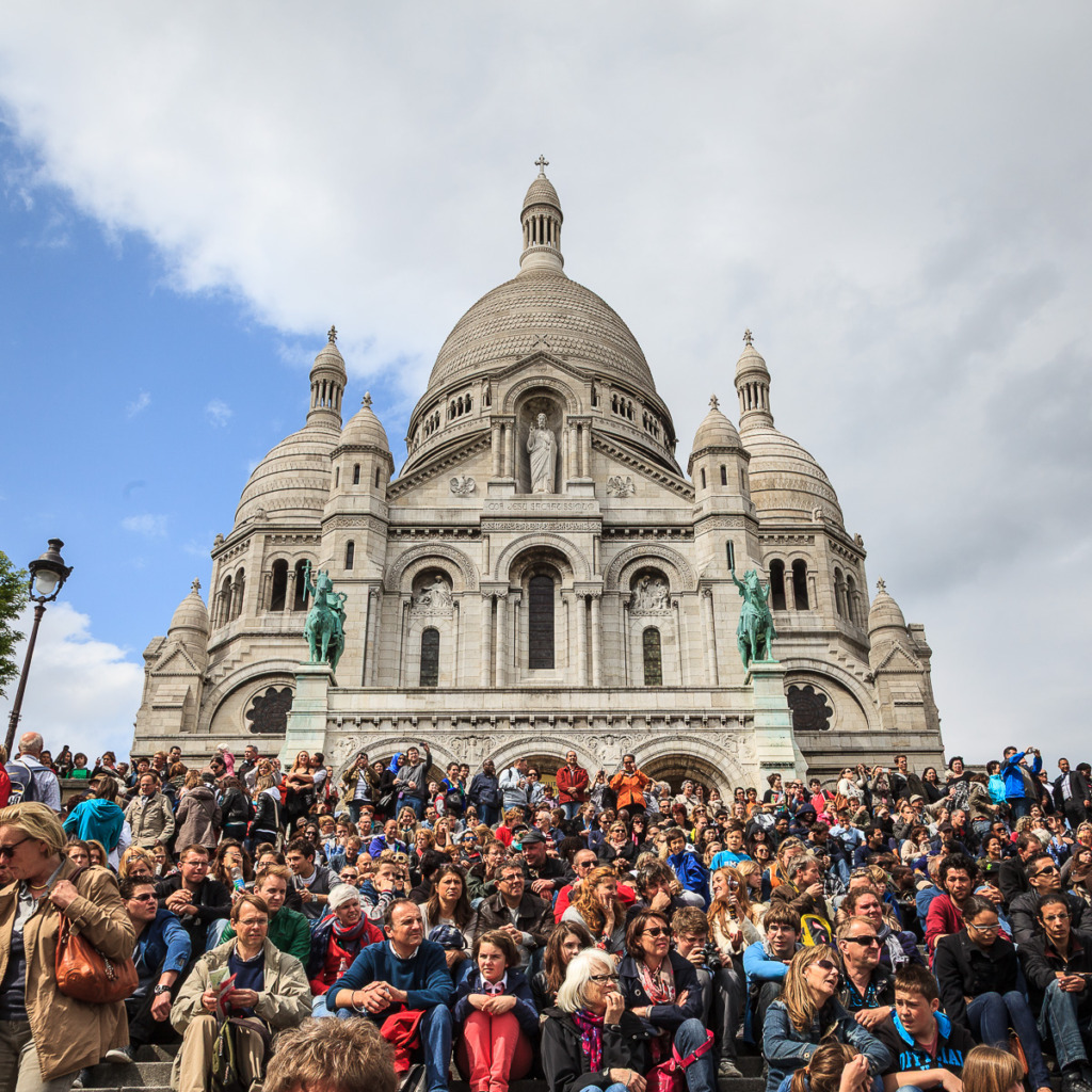 Sacre Coeur in Paris with a crowd of people on the steps in front.